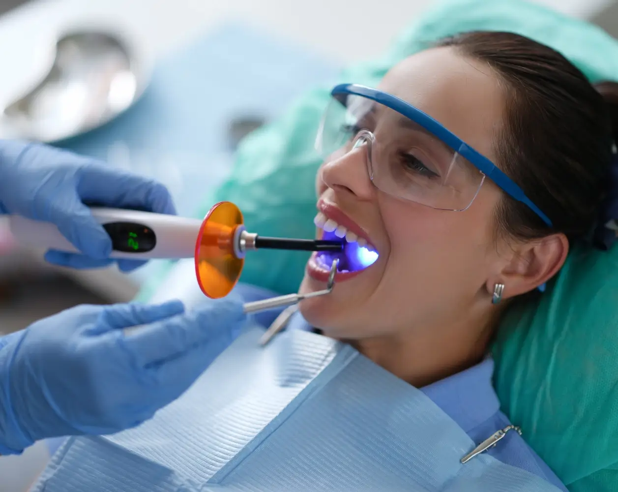 Dentist using curing light on patient's teeth.