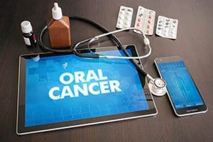 Tablet displaying 'Oral Cancer' with medical tools and medication nearby.