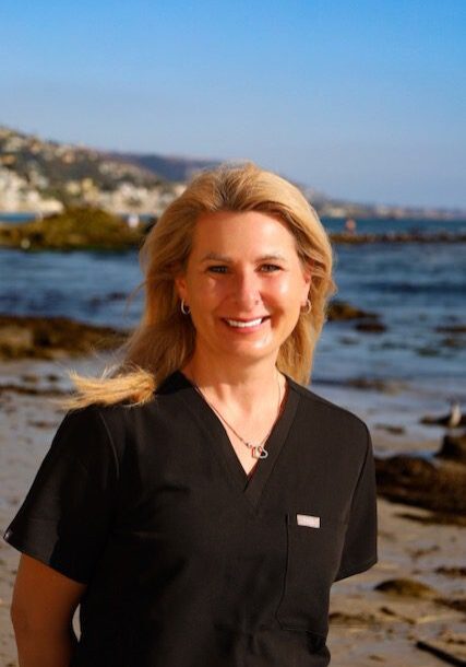 Smiling woman in black scrubs by the seaside.